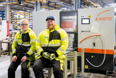 Kahden Kimetin työntekijän ryhmäkuva sahauskoneen äärellä tuotantotiloissa. Kuvassa näkyy ammattimainen työote, moderni koneympäristö ja sertifioitu laatuajattelu osana arkea.