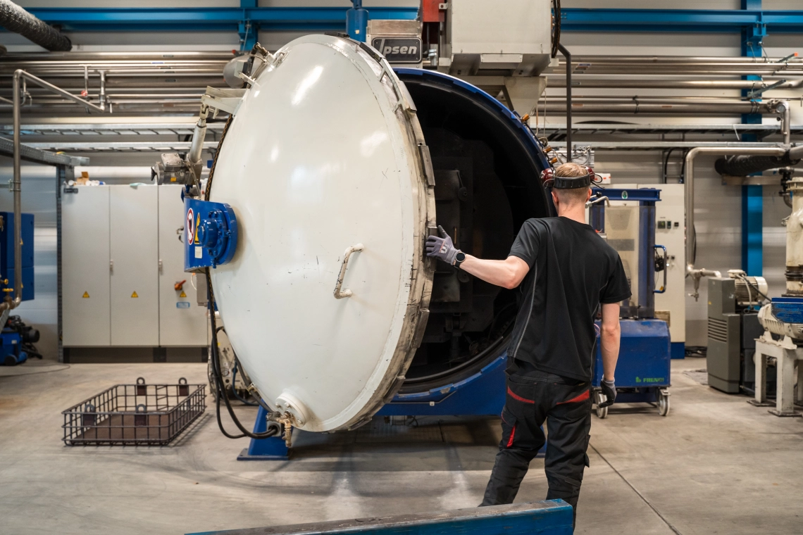 Asiantuntija tarkkailee modernissa vakuumiuunissa käsiteltäviä teräskomponentteja Stén-konsernin Muuramen yksikössä